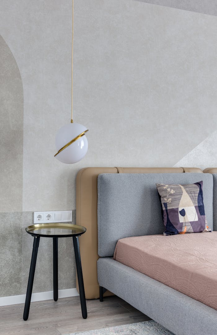 home-img Comfortable bed with colorful pillow near bedside table under lamp with creative design
